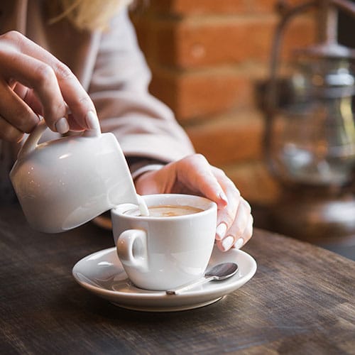 pouring cream into coffee