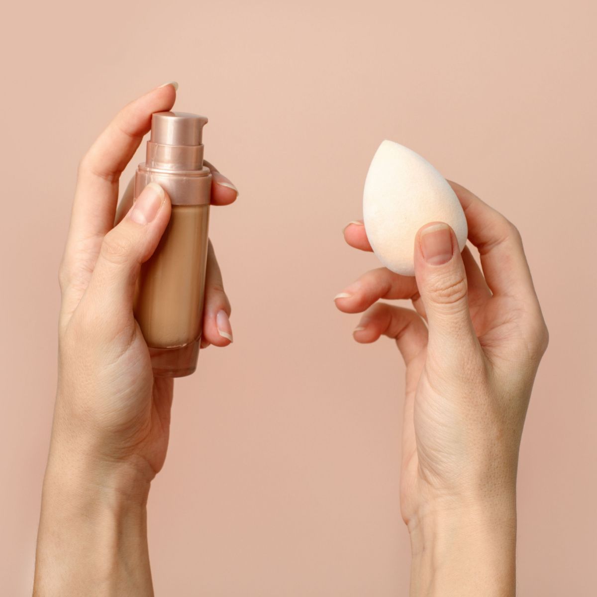 beauty blender foundation in hands pink background