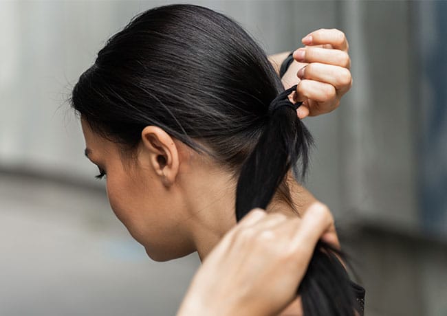 woman-ties-hair-ponytail