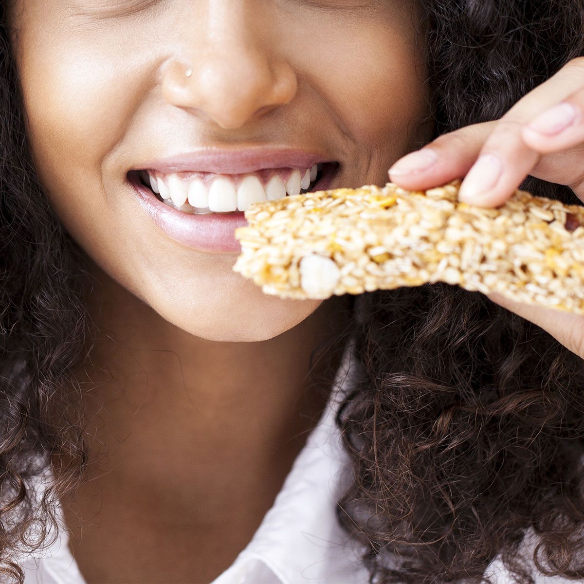 woman biting into granola bar