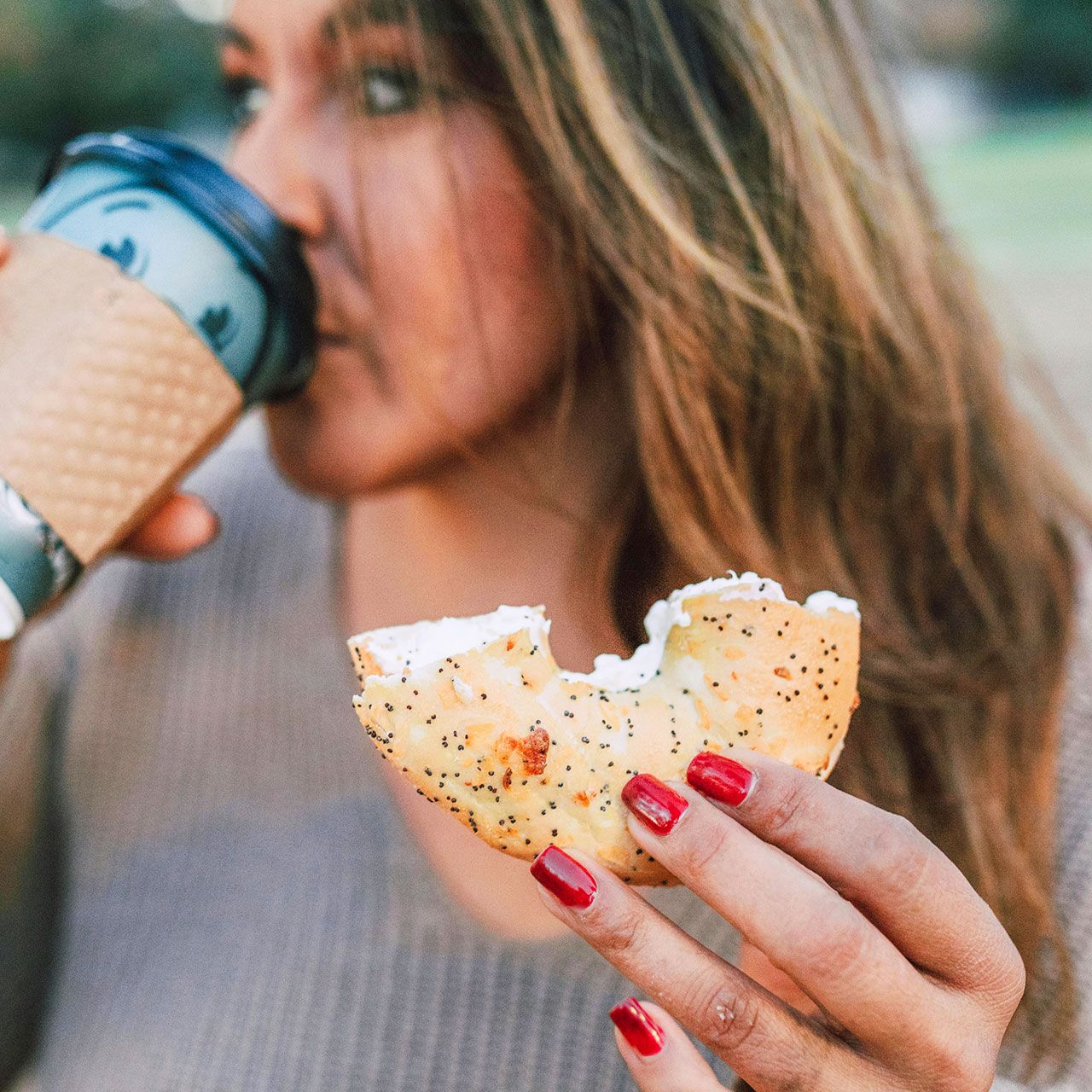 woman drinking coffee eating bagel