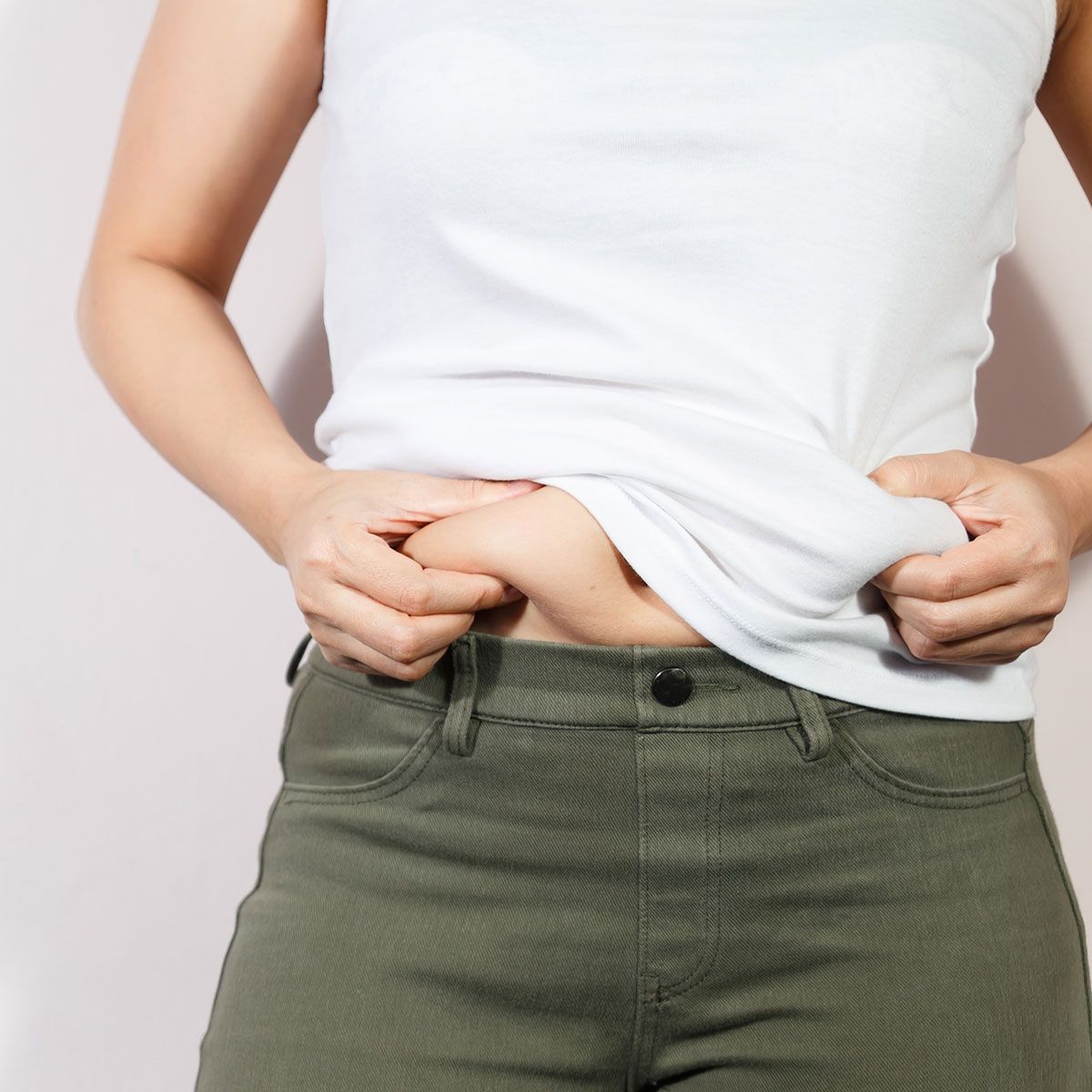 woman pinching her stomach white crop top