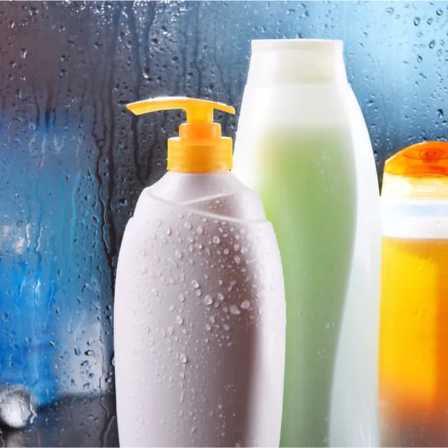 isolated bottles of shampoo within shower covered with water droplets multicolored