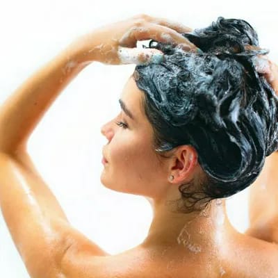 woman scrubbing her hair with shampoo in the shower blue liquid black hair