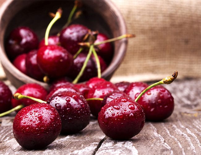 water-sprinkled cherries spilling out of a basket