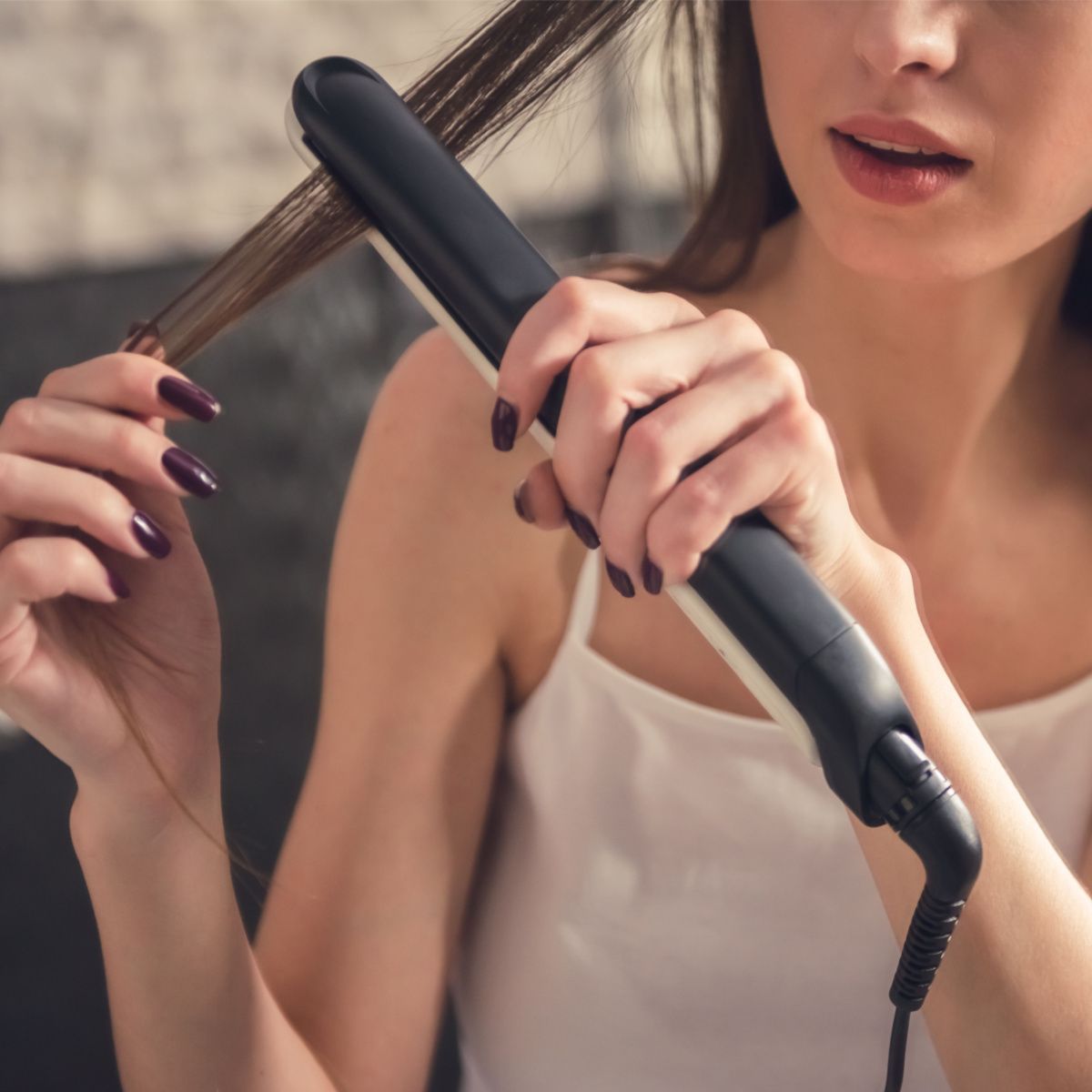 woman straightening her hair burning hair damage