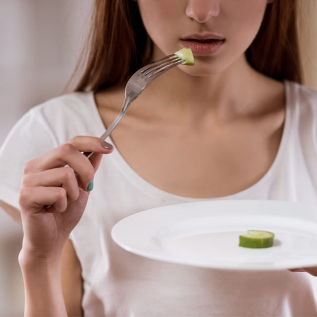 woman eating small bites of food almost empty plate