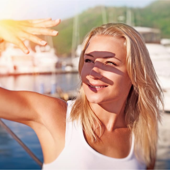 woman with hand in front of face to prevent sunlight shadow on face