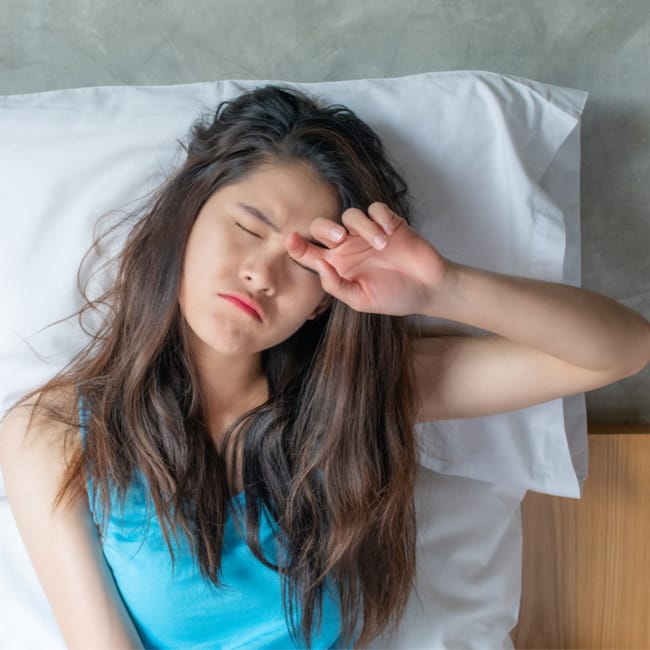 woman trying to sleep on pillowcase closed eyes sunlight