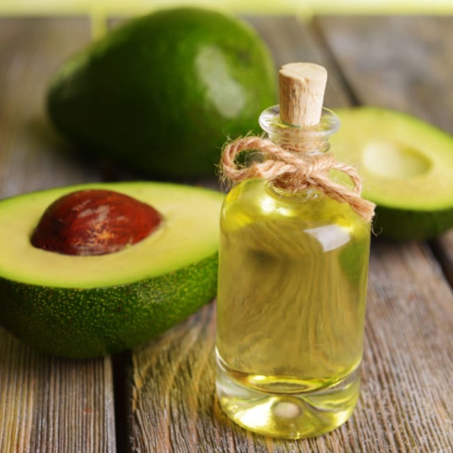 avocado oil in glass bottle next to freshly sliced avocados