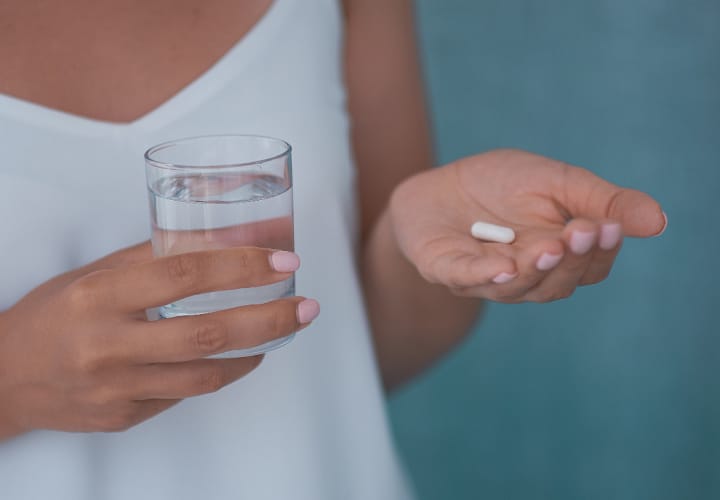 Woman holding a supplement with water
