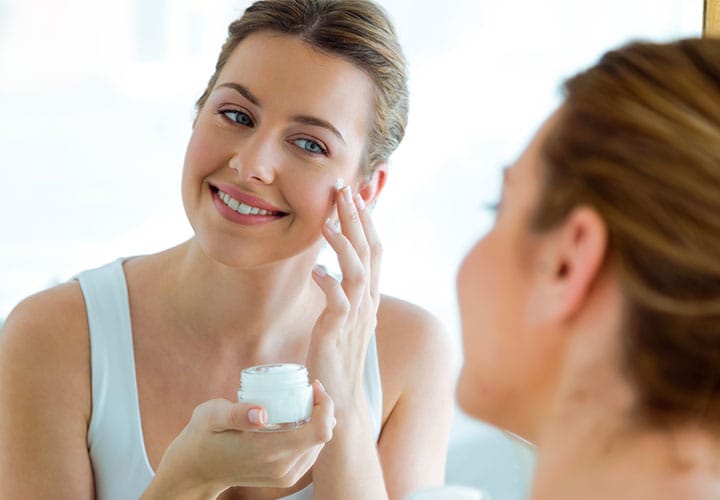 Woman applying moisturizer.