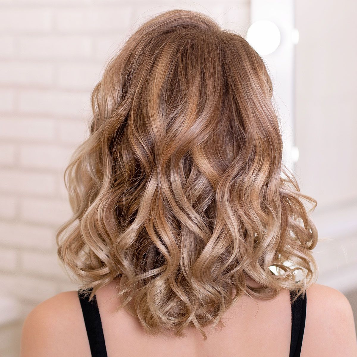 dirty blonde hair behind salon wavy hair shiny curls black straps