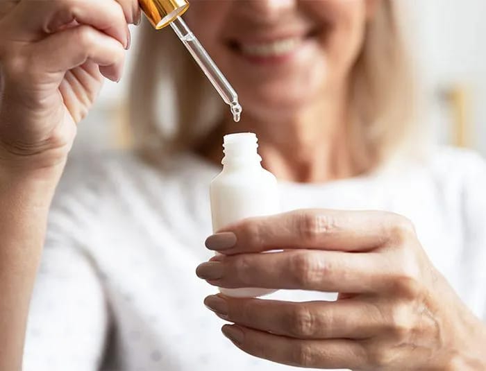Mature woman holding up a skincare product
