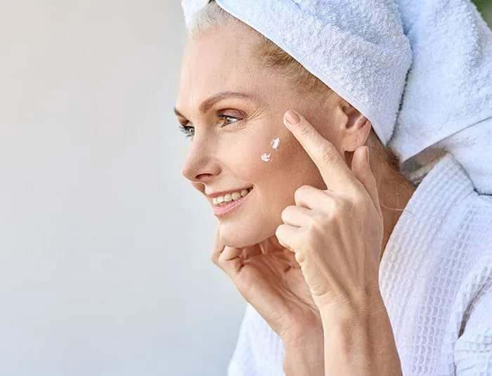 Older woman applying face moisturizer to her face