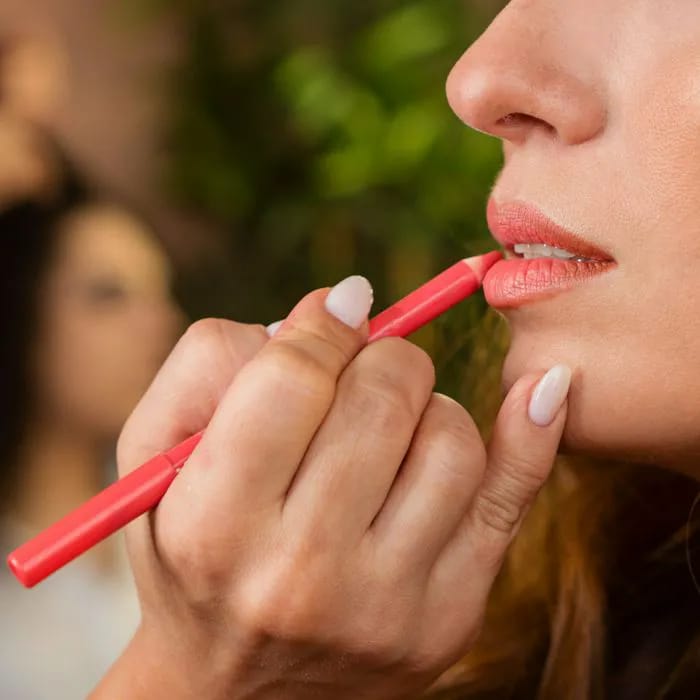 woman applying coral lip liner makeup artists client
