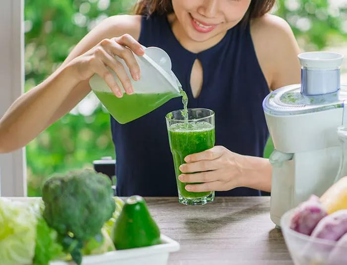 woman pouring fresh juice made from vegetables