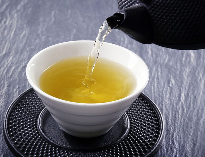 green tea pouring from a cast iron pot