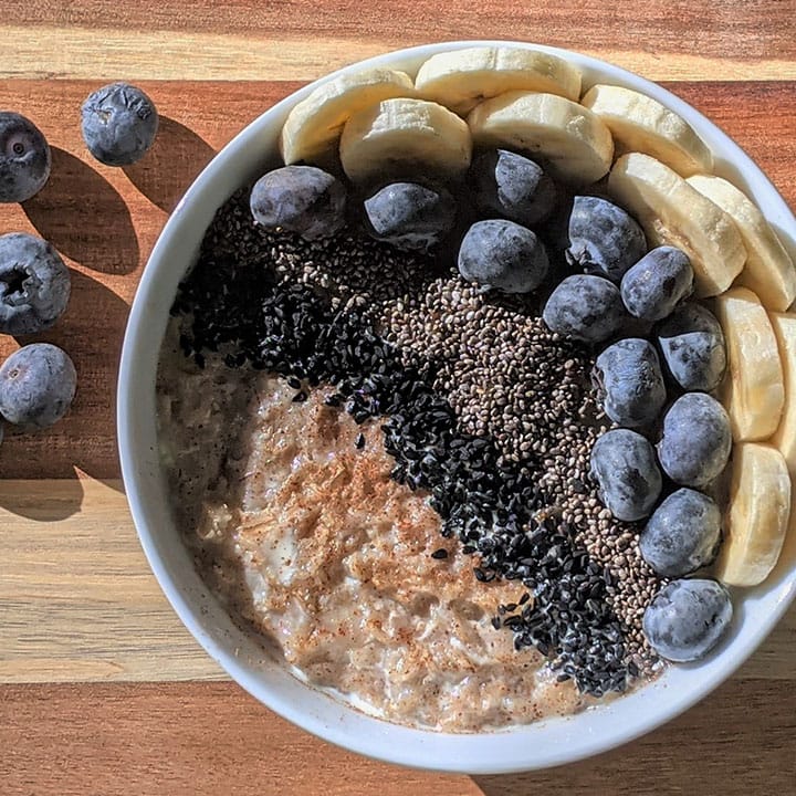 bowl of oatmeal topped with bananas, blueberries, and chia seeds