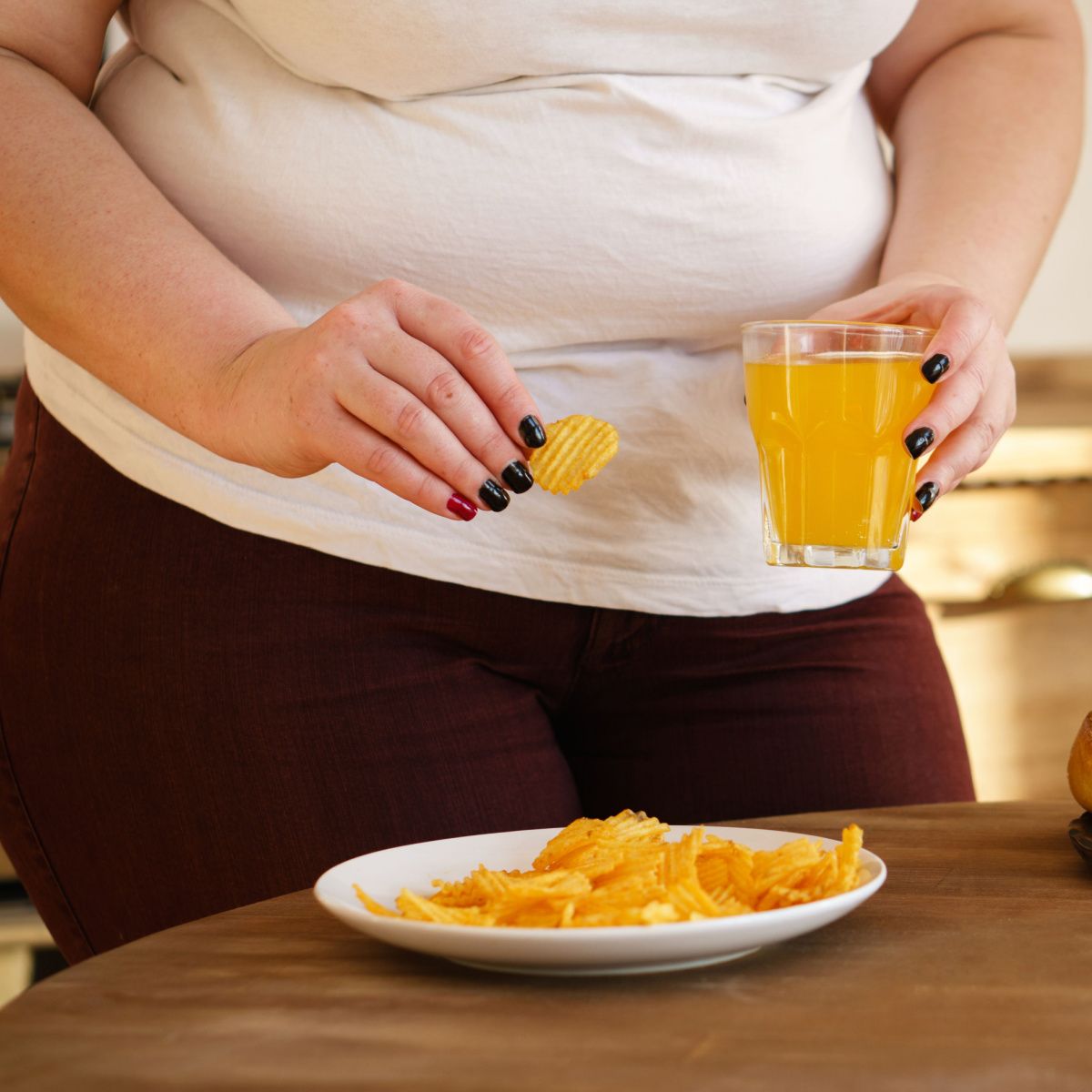 woman with belly fat drinking soda and chips