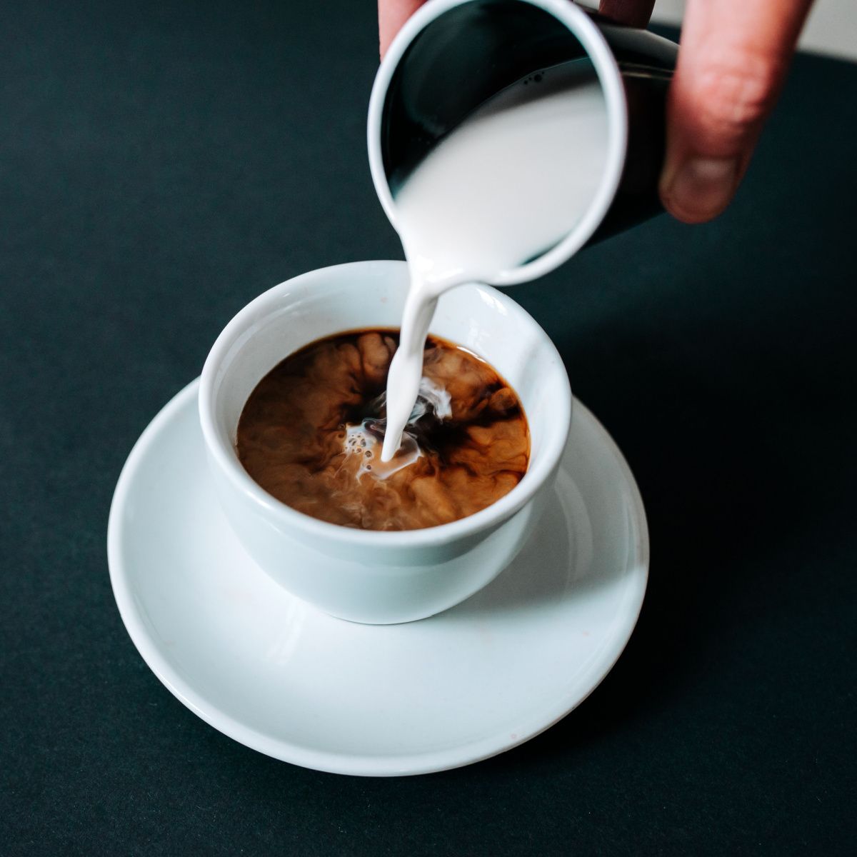coffee creamer being poured into coffee