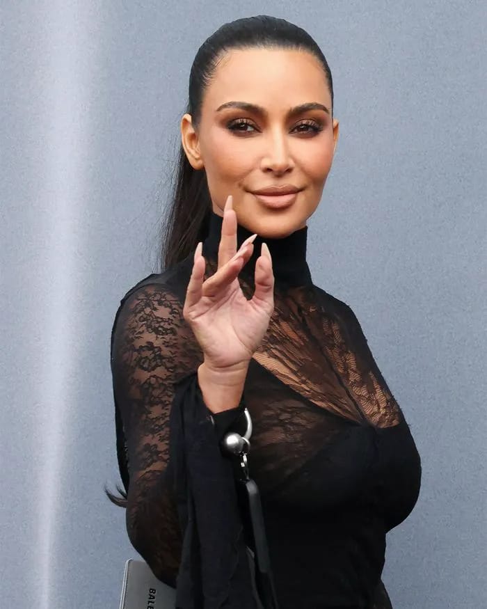 Close-up of Kim Kardashian waving at Balenciaga Fashion Week event.