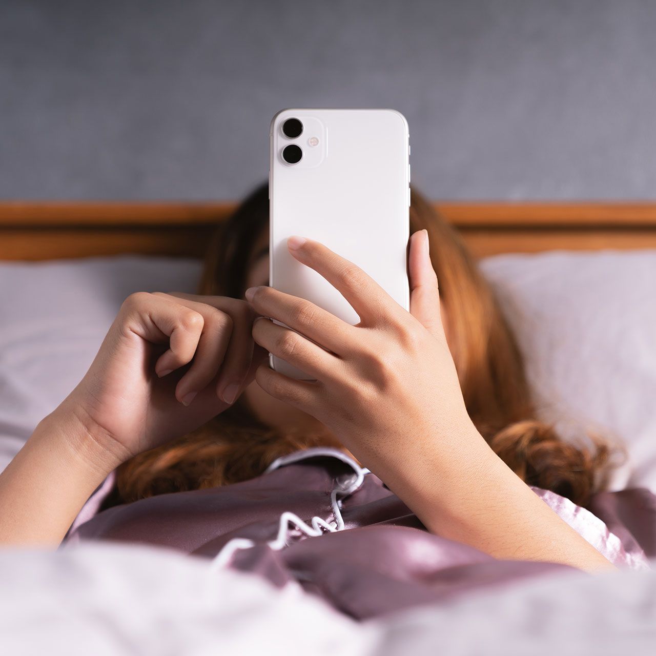 woman-using-iphone-bed