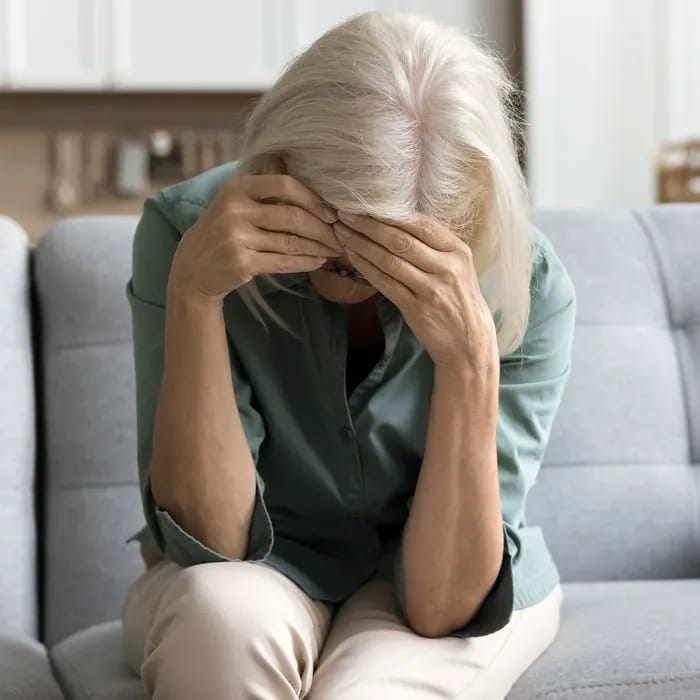 Frustrated older woman touching her head in distress.