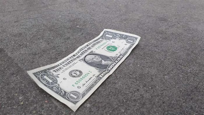 "Dollar bill on a sidewalk"