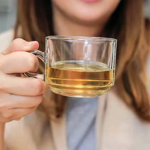 woman drinking white tea in a glass mug