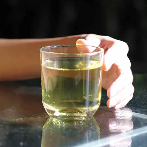 woman holding white tea in a clear mug