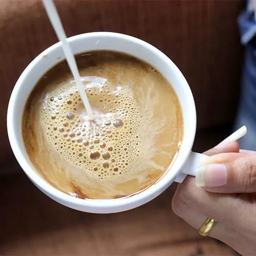 pouring creamer into coffee
