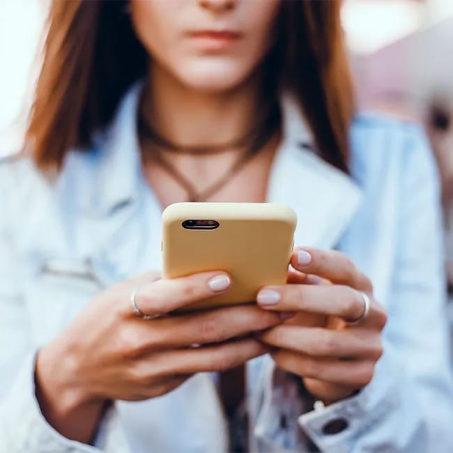 Woman using an iPhone with a bright yellow case.