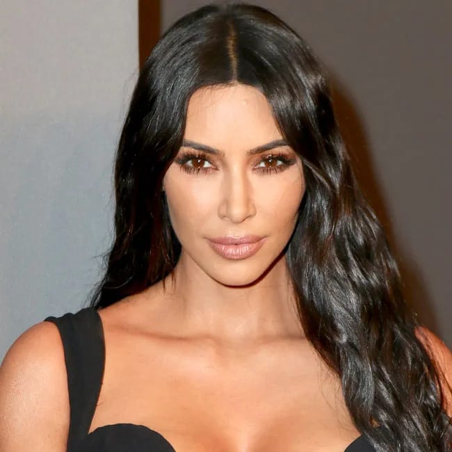 Kim Kardashian poses confidently in glamorous fashion ensemble.