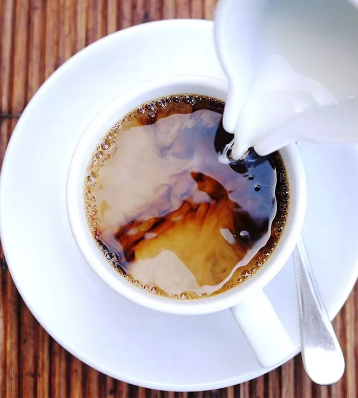 Pouring creamer into coffee