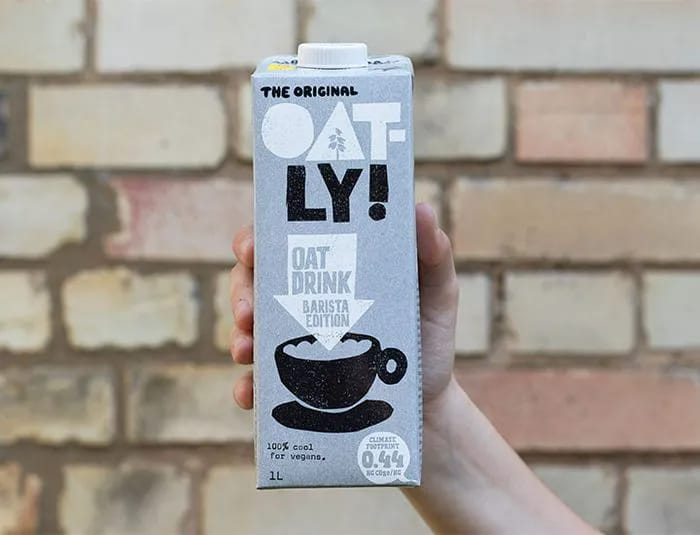 Hand holding a carton of Oatly