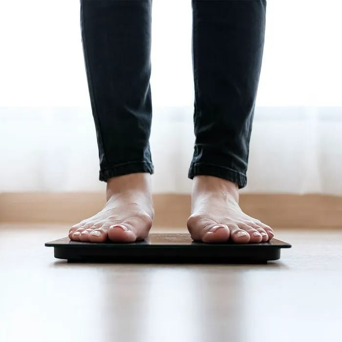 "Woman standing on a scale wearing jeans"
