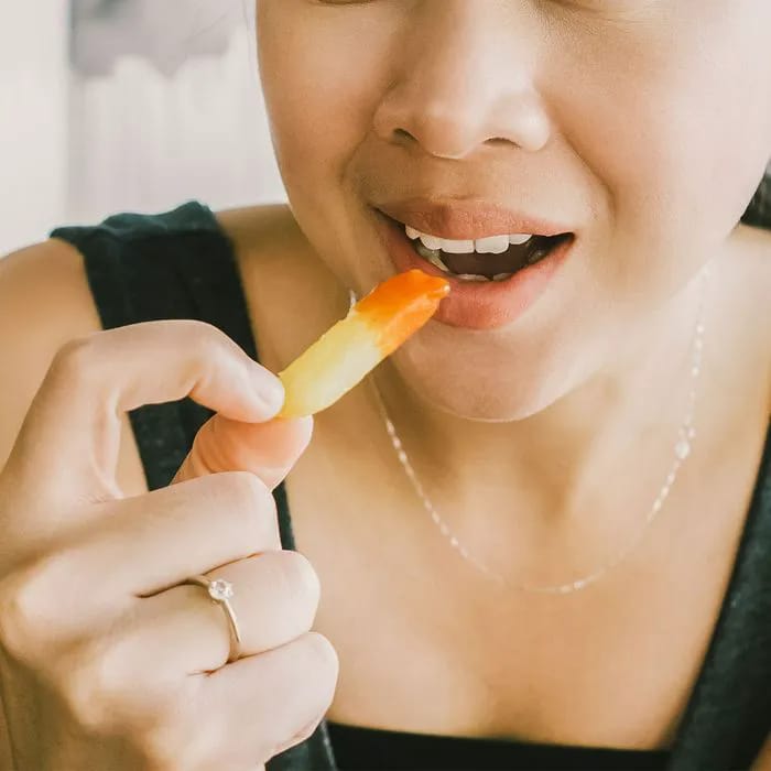 Woman eating a French fry dipped in ketchup