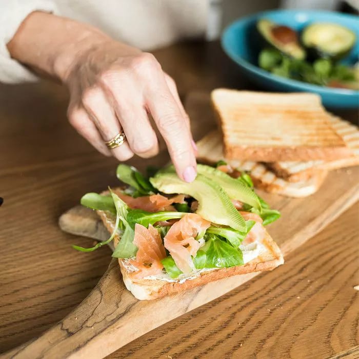 "Woman making avocado toast sandwich"