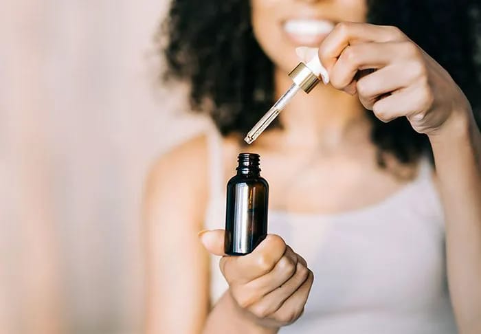 woman-smiling-skincare-serum-bottle