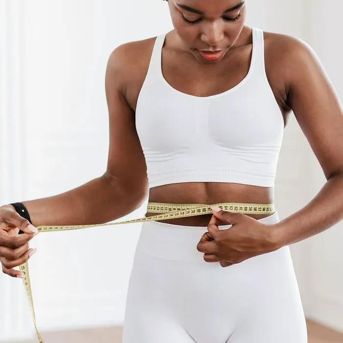 Athletic girl measuring her stomach for fitness progress.