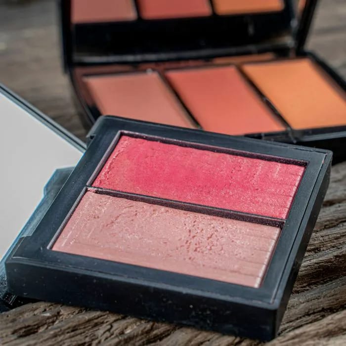 compact blush shimmering products table wooden background