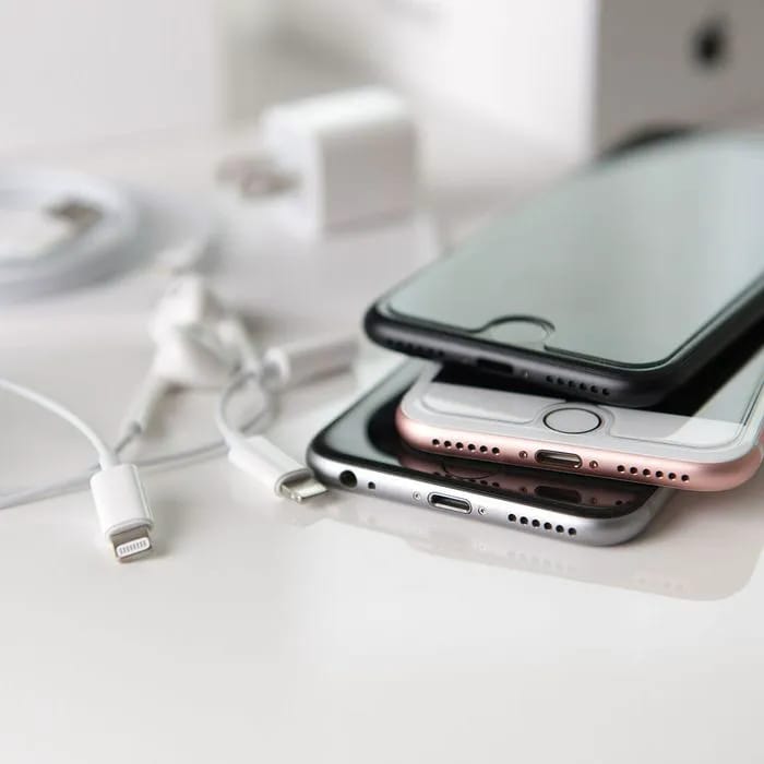 Stack of iPhones with chargers illustrating accessory overload.