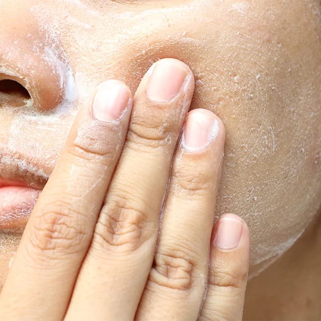 foaming white cleanser on face washing skin with fingers complexion close-up