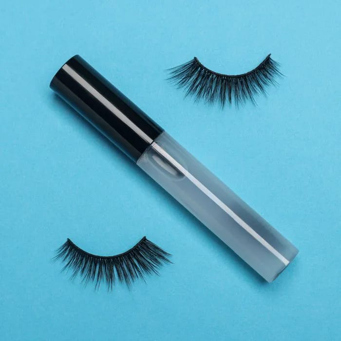lash serum plastic tube eyelash glue fake lashes blue background