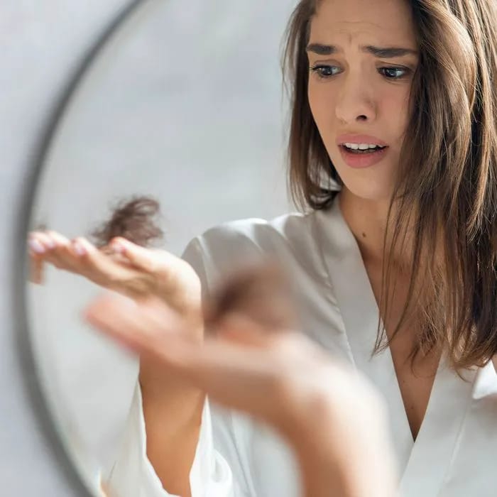 womans hair falling out holding hair in hand