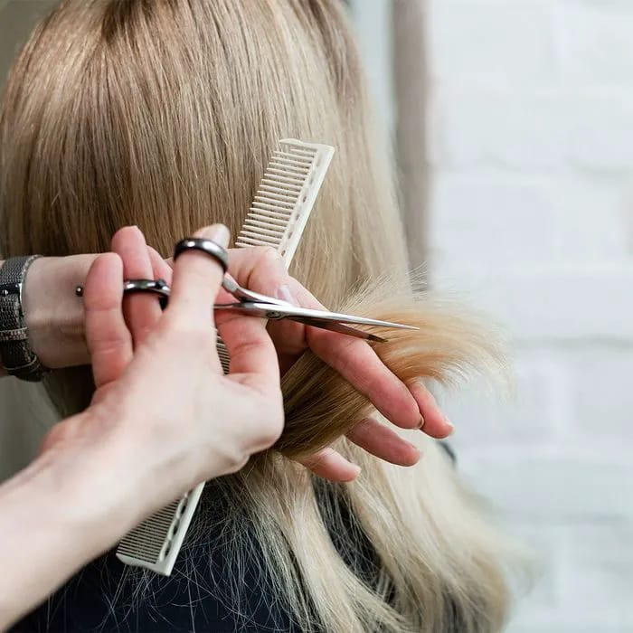 "Blonde woman getting a haircut at a salon"