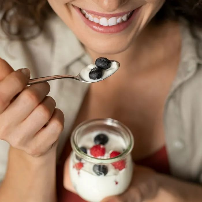 woman eating yogurt topped with berries