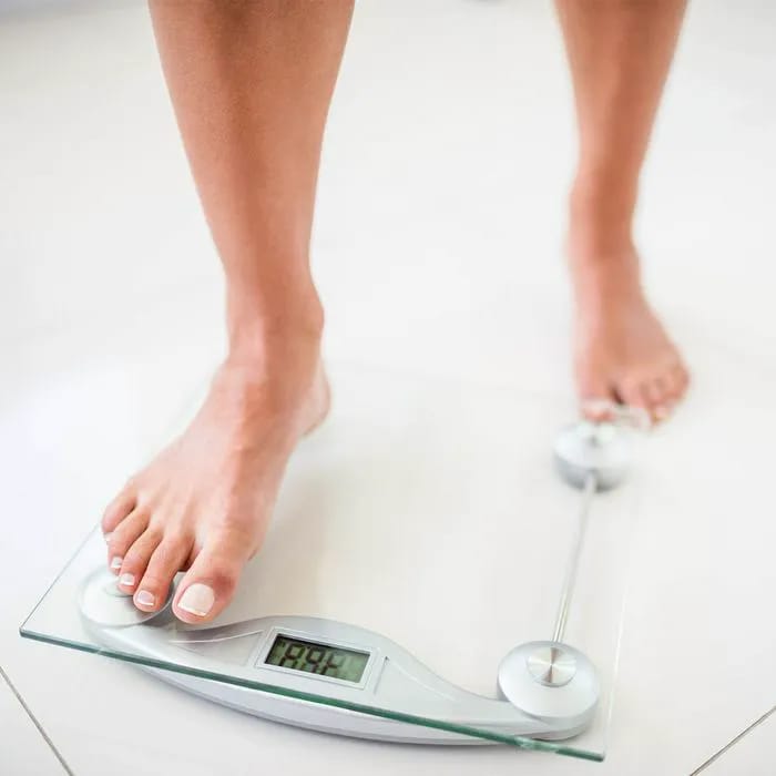Woman stepping onto a bathroom scale for weight check.
