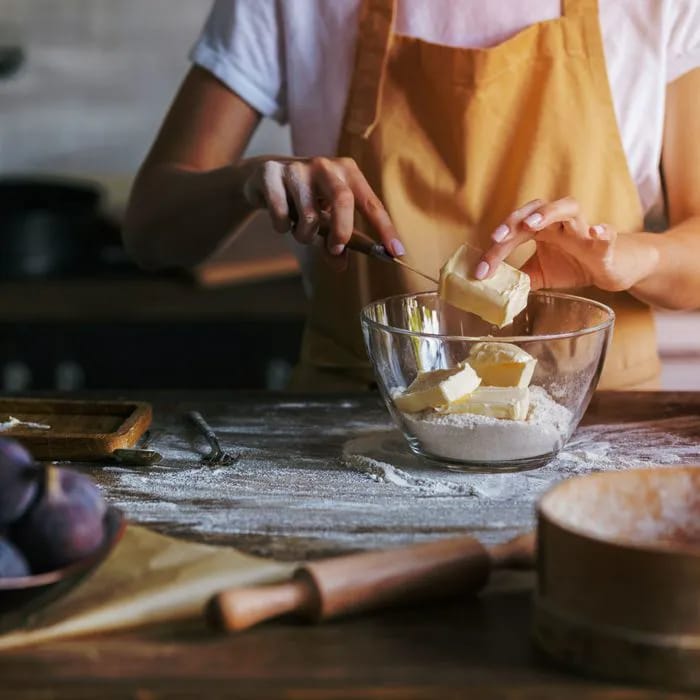 woman adding margarine to bowl